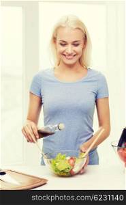 healthy eating, vegetarian food, cooking, dieting and people concept - smiling young woman dressing vegetable salad at home