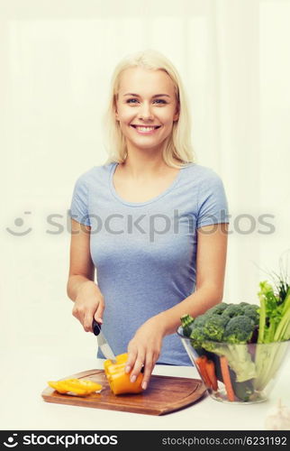 healthy eating, vegetarian food, cooking, dieting and people concept - smiling young woman chopping vegetables at home