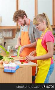 Healthy eating, vegetarian food, cooking, weight loss and people concept. Happy young couple woman and man in kitchen at home preparing fresh vegetables salad meal