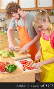 Healthy eating, vegetarian food, cooking, weight loss and people concept. Happy young couple woman and man in kitchen at home preparing fresh vegetables salad meal