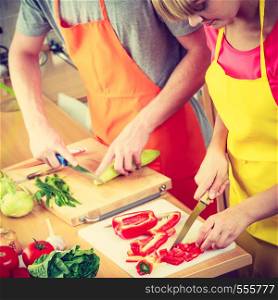 Healthy eating, vegetarian food, cooking, weight loss and people concept. Closeup couple woman and man in kitchen at home slicing vegetables for salad