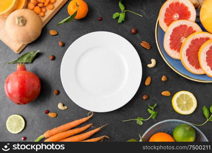 healthy eating, vegetarian food, diet and culinary concept - empty white plate and different vegetables and fruits on on slate table. plate, vegetables and fruits on on slate table