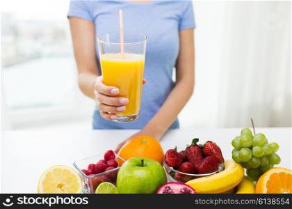 healthy eating, vegetarian food, diet and people concept - close up of woman holding orange juice glass with fruits at home