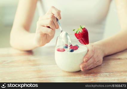 healthy eating, vegetarian food, diet and people concept - close up of woman hands with yogurt and berries on table