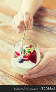 healthy eating, vegetarian food, diet and people concept - close up of woman hands with yogurt and berries on table