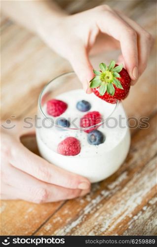 healthy eating, vegetarian food, diet and people concept - close up of woman hands with yogurt and berries on table