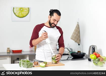 healthy eating, vegetarian food, diet and people concept - happy young man with blender and fruits cooking at home kitchen. man with blender cooking food at home kitchen