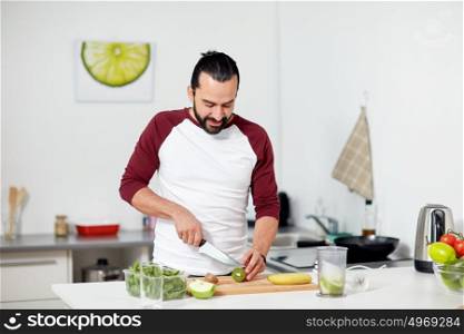 healthy eating, vegetarian food, diet and people concept - happy young man with blender and fruits cooking at home kitchen. man with blender and fruit cooking at home kitchen