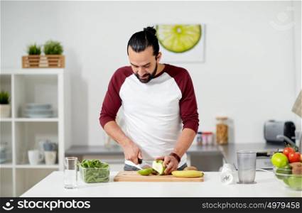 healthy eating, vegetarian food, diet and people concept - happy young man with blender and fruits cooking at home kitchen. man with blender and fruit cooking at home kitchen