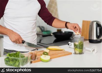 healthy eating, vegetarian food, diet and people concept - man with blender and fruits cooking at home kitchen. man with blender and fruit cooking at home kitchen
