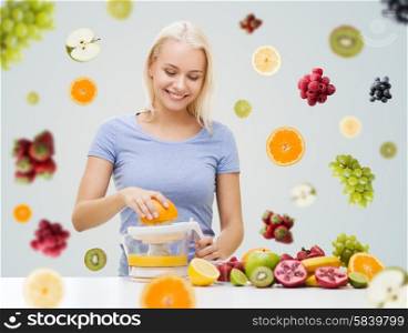 healthy eating, vegetarian food, diet, detox and people concept - smiling woman with squeezer squeezing fruit juice over fruits and berries on gray background
