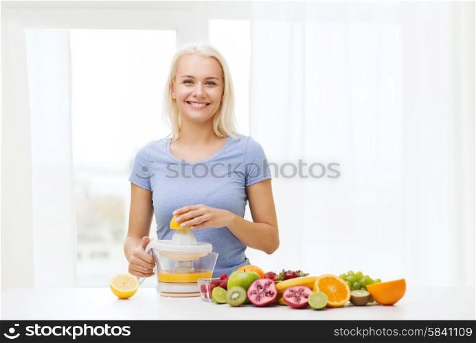 healthy eating, vegetarian food, diet, detox and people concept - smiling woman with squeezer squeezing fruit juice at home