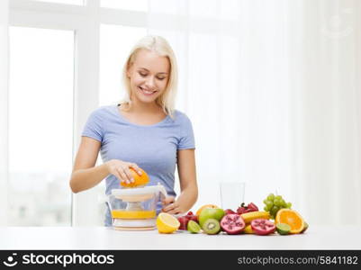 healthy eating, vegetarian food, diet, detox and people concept - smiling woman with squeezer squeezing fruit juice at home