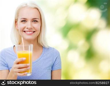healthy eating, vegetarian food, diet, detox and people concept - smiling woman drinking orange juice or shake from glass over green natural background