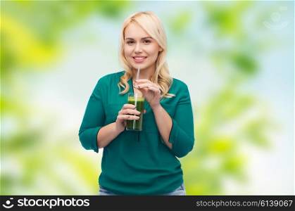 healthy eating, vegetarian food, diet, detox and people concept - smiling young woman drinking green vegetable juice or smoothie from glass over green natural background
