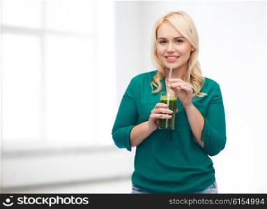 healthy eating, vegetarian food, diet, detox and people concept - smiling young woman drinking green vegetable juice or smoothie from glass over white room background