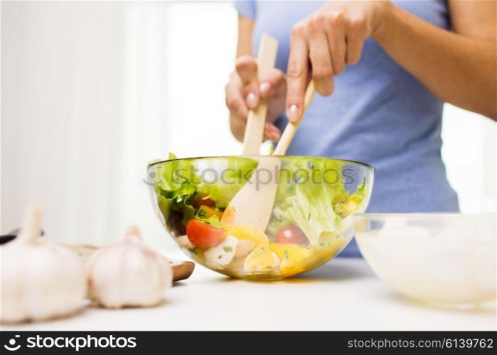 healthy eating, vegetarian food, dieting and people concept - close up of young woman cooking vegetable salad at home