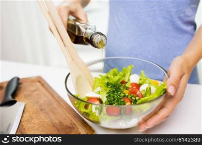 healthy eating, vegetarian food, dieting and people concept - close up of young woman dressing vegetable salad with olive oil at home