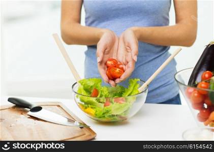healthy eating, vegetarian food, dieting and people concept - close up of young woman cooking vegetable salad and adding tomatoes at home