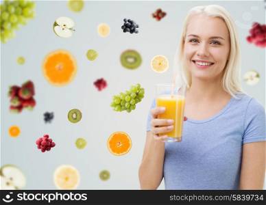 healthy eating, vegetarian food, dieting and people concept - smiling woman drinking orange juice or shake from glass over fruits and berries on gray background