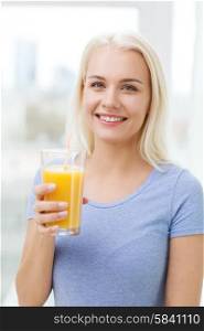 healthy eating, vegetarian food, dieting and people concept - smiling woman drinking orange juice or shake from glass at home
