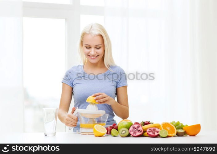 healthy eating, vegetarian food, dieting and people concept - smiling woman with squeezer squeezing fruit juice at home