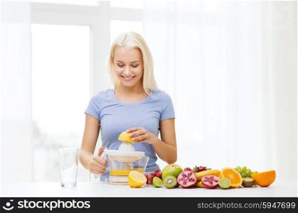healthy eating, vegetarian food, dieting and people concept - smiling woman with squeezer squeezing fruit juice at home