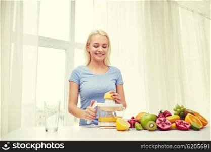 healthy eating, vegetarian food, dieting and people concept - smiling woman with squeezer squeezing fruit juice at home