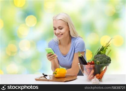 healthy eating, vegetarian food, dieting and people concept - smiling young woman with smartphone cooking vegetables over summer green holidays lights background