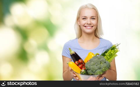 healthy eating, vegetarian food, dieting and people concept - smiling young woman with bowl of vegetables over green natural background