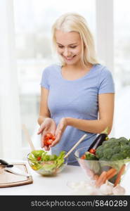 healthy eating, vegetarian food, dieting and people concept - smiling young woman cooking vegetable salad at home