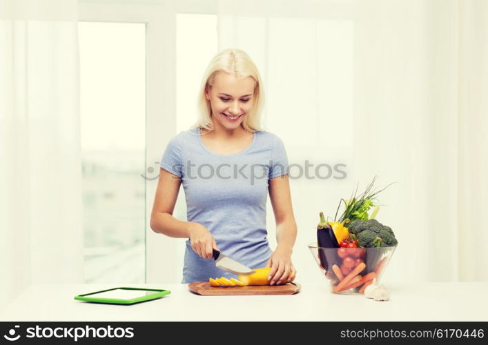 healthy eating, vegetarian food, dieting and people concept - smiling young woman cooking vegetables with tablet pc computer at home