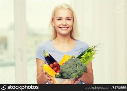 healthy eating, vegetarian food, dieting and people concept - smiling young woman with bowl of vegetables at home