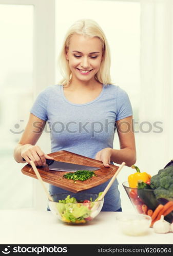 healthy eating, vegetarian food, dieting and people concept - smiling young woman cooking vegetable salad at home