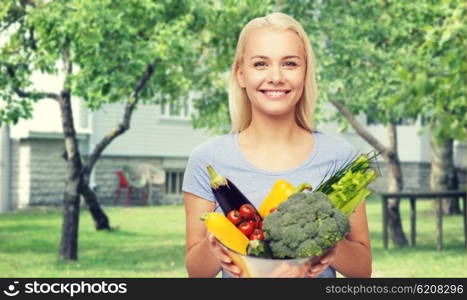 healthy eating, vegetarian food, dieting and people concept - smiling young woman with bowl of vegetables over house and summer garden background