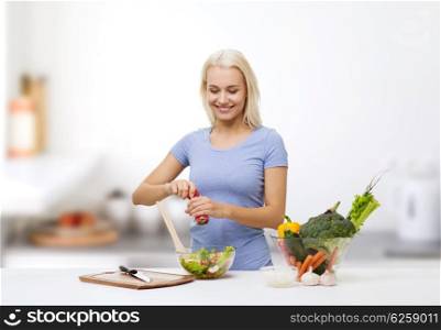 healthy eating, vegetarian food, dieting and people concept - smiling young woman cooking vegetable salad over kitchen background