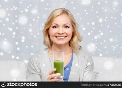 healthy eating, vegetarian food, dieting, detox and people concept - smiling middle aged woman drinking green fresh vegetable juice or smoothie from glass at home over snow