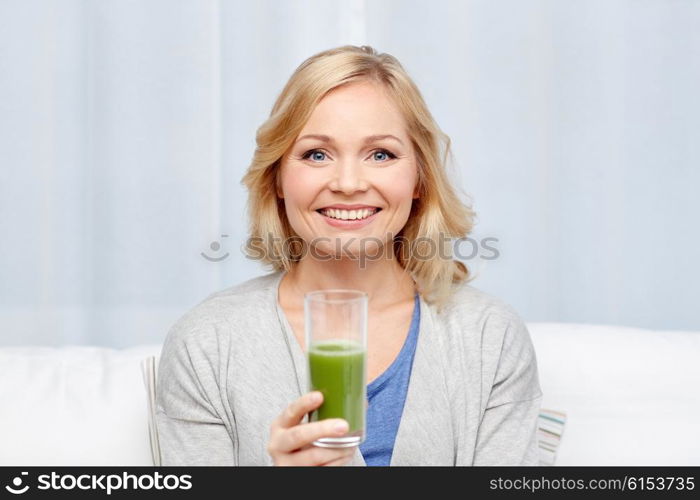 healthy eating, vegetarian food, dieting, detox and people concept - smiling middle aged woman drinking green fresh vegetable juice or smoothie from glass at home