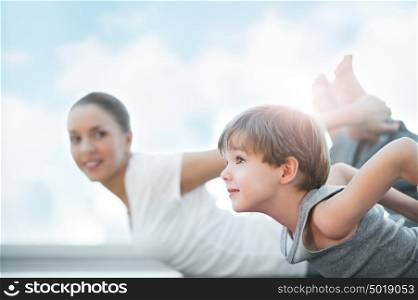 Healthy family - mother and son doing exercises against blue sky