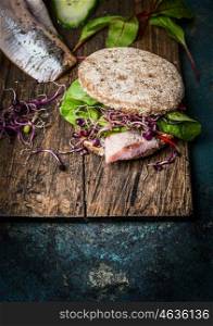 Healthy fish sandwich with grain bread and fish on rustic cutting board