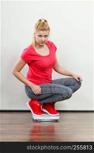 Healthy fit life style, controling body concept. Woman wearing sportswear, leggings and trainers standing on weight machine.. Woman wearing sportswear standing on weight machine