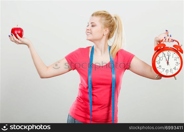 Healthy fit lifestyle, getting ready for diet concept. Happy sporty woman holding red old clock, apple and measuring tape.. Happy woman holding clock, apple and measuring tape