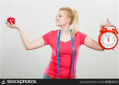 Healthy fit lifestyle, getting ready for diet concept. Happy sporty woman holding red old clock, apple and measuring tape.. Happy woman holding clock, apple and measuring tape