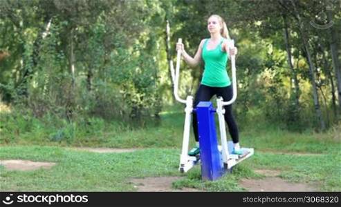 Healthy fit young woman exercising on a trainer in the garden
