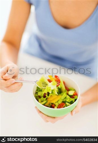healthy food and kitchen concept - woman eating salad with vegetables