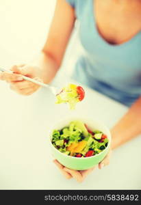 healthy food and kitchen concept - woman eating salad with vegetables