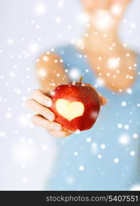 healthy food and lifestyle - woman hand holding red apple with heart shape