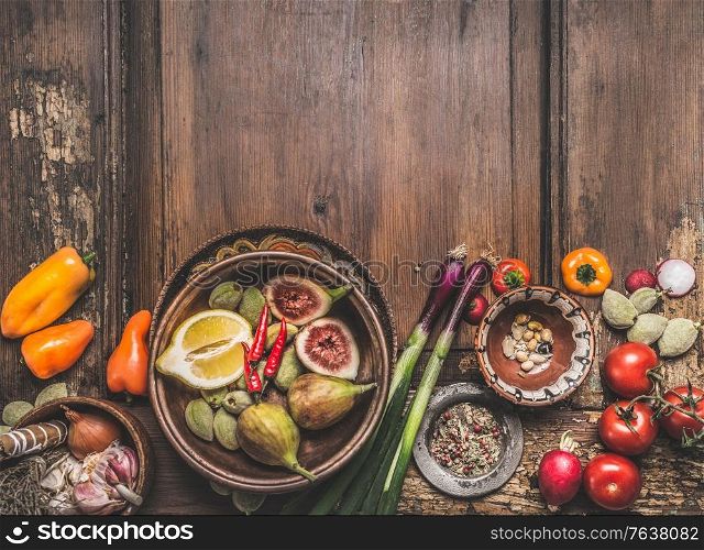 Healthy food and snack background. Bowls with tasty ingredients of Mediterranean cuisine: various vegetables, olives, pickled pepperoni and figs on wooden rustic table. Top view. Place for text