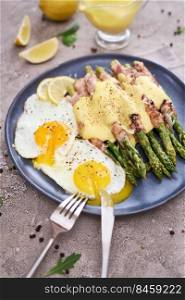 Healthy food - Asparagus wrapped with bacon and spices on a plate.. Healthy tasty breakfast - Asparagus wrapped with bacon and fried eggs on a plate