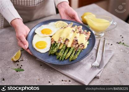 Healthy food - Asparagus wrapped with bacon and spices on a plate.. Healthy tasty breakfast - Asparagus wrapped with bacon and fried eggs on a plate